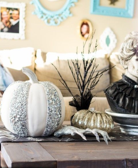 a coffee table with an embellished pumpkin, a branch arrangement and a bust for Halloween