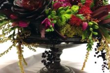 05 a black bowl with succulents, cascading greenery and branches, dark blooms and a sprakling red skull
