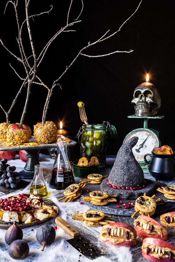 a buffet table styled with a sparky witch hat, some potion in bottles, a skull candleholder and some creepy treats