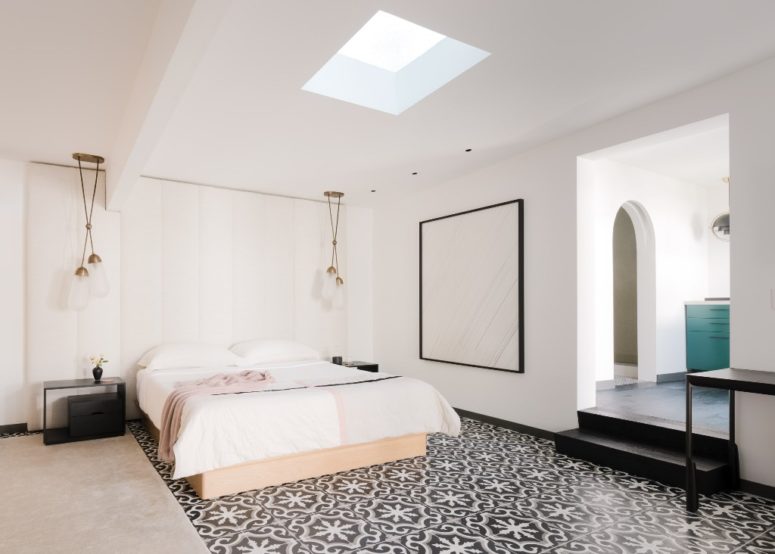 The master bedroom is done with a skylight, some pendant lamps, a tile floor and a statement artwork
