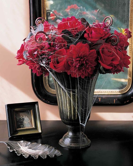 a moody vintage urn with sumptuous red blooms and some spiderweb is a traditional Halloween option that always works