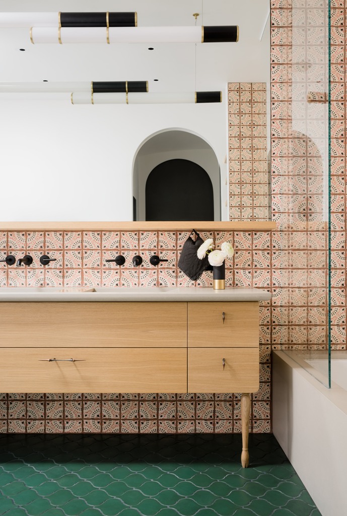 The master bathroom shows off unique tiles, a wooden vanity and a bright green floor