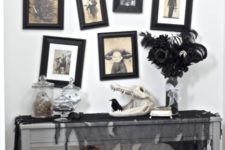 08 a Halloween console with black tulle, skulls of animals and humans, a spooky gallery wall and a black feather arrangement