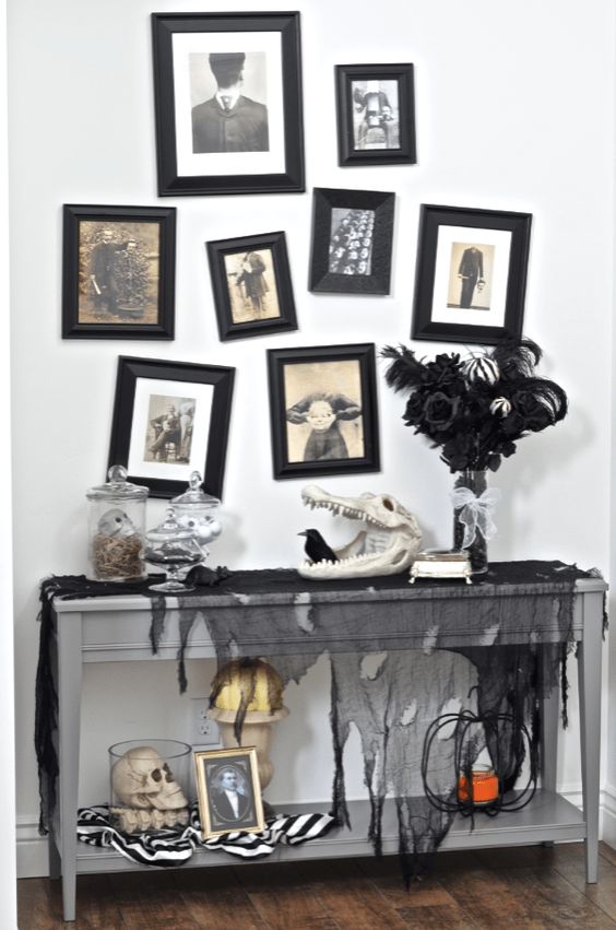 a Halloween console with black tulle, skulls of animals and humans, a spooky gallery wall and a black feather arrangement
