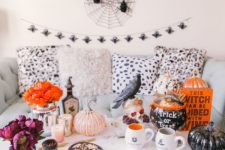 08 a whimsy coffee table with faux pumpkins, blackbirds, candles, a sugar skull, some witch potion and a book plus bold blooms