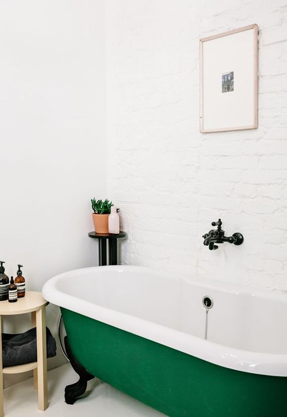 an emerald clawfoot bathtub is a bright touch to your simple and neutral bathroom, and black touches will add drama
