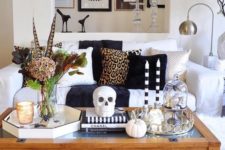 10 Halloween coffee table decor with a skull, skulls in a cloche, pumpkins, dried blooms and feathers plus candles