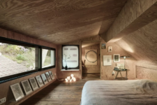10 The master bedroom is designed like a cabin and is all clad with light-colored plywood, there some lights, art and a work space
