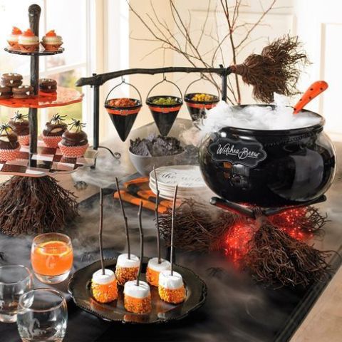 a stylish Halloween food and drink station with a cauldron with drinks, a broom with witch hats for food serving, drinks and sweets that match