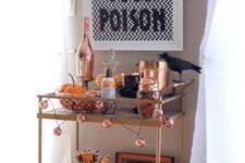 12 a chic Halloween bar cart with a sign, blackbirds, a garland and lots of copper touches and details