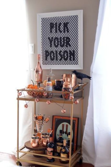 a chic Halloween bar cart with a sign, blackbirds, a garland and lots of copper touches and details