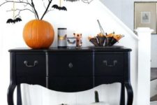 12 an elegant black console table with white pumpkins, an orange pumpkin as a vase, black branches with bats and bat candleholders