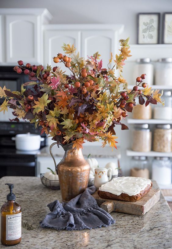 a beautiful fall arrangement of fall leaves and berries in a vintage metal jug is amazing for home decor