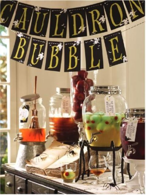 a cool drink station decorated with a bunting over the table, a broom stirrer, eyeballs and a spellbook