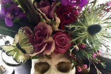 14 a skull centerpiece with a lush floral arrangement in purple, pink, green, with thistles and butterflies plus large leaves