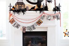 16 a bold Halloween mantel with a colorful bunting, blackbirds, feathers, a cage, candles and pumpkins