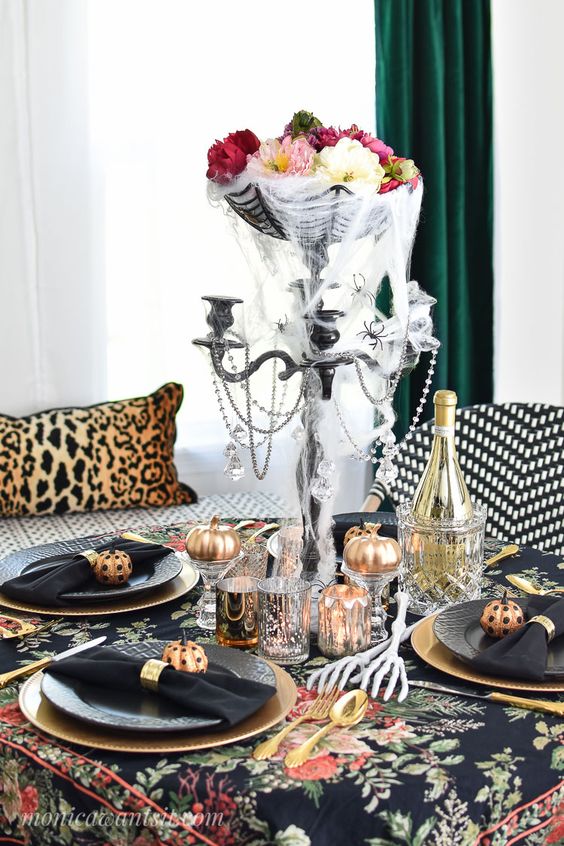 a bold Halloween centerpiece of a black bowl with a spiderweb, beads and some flower heads in the bowl