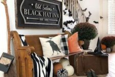 19 a gorgeous Halloween entryway with large pumpkins, black and white fabric, a witch broom, hat, shoes and some bats