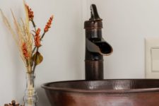 19 a hammered copper sink and faucet, a pumpkin, pinecone and a dried arrangement for pretty fall bathroom decor