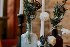 20 a chic Halloween centerpiece of glass bottles with blooms and dried greenery plus some tall candles
