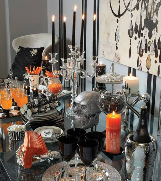 a refined Halloween drink bar with black and white candles, black glasses, touches of orange and sparkly silver details