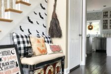 21 a Halloween entryway with letters, plaid elements, a broom of twigs, a sign and some pumpkin pillows
