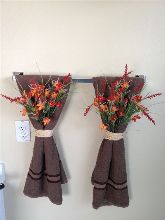 an easy and pretty bathroom decoration with brown towels and bright fall blooms attached to them