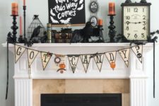 22 a chic Halloween mantel with a bunting, candles, blackbirds and bats, a clock and cages plus a sign on the wall