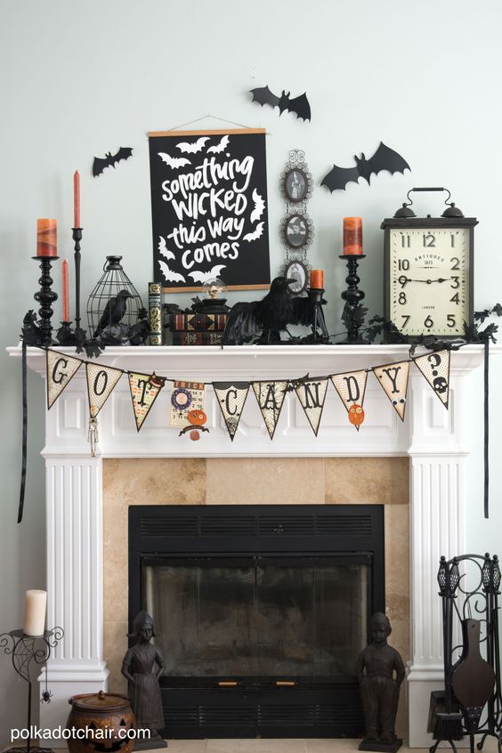 a chic Halloween mantel with a bunting, candles, blackbirds and bats, a clock and cages plus a sign on the wall
