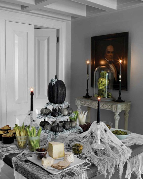 a creative Halloween centerpiece of a stand with glitter silver and black pumpkins plus pale greenery