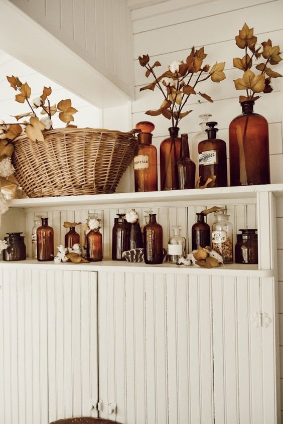 bathroom shelves with amber bottles, fall leaves, cotton and dried herbs will brign a fall spirit to the space