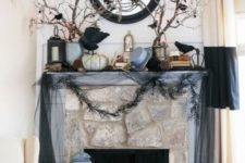 23 a haunted Halloween mantel with blackbirds, branches, garlands, a mirror and some pumpkins