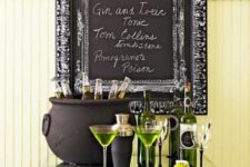 23 a stylish Halloween drink station with green bottles and sheer glasses, green drinks and a cauldron with bottles plus a sign