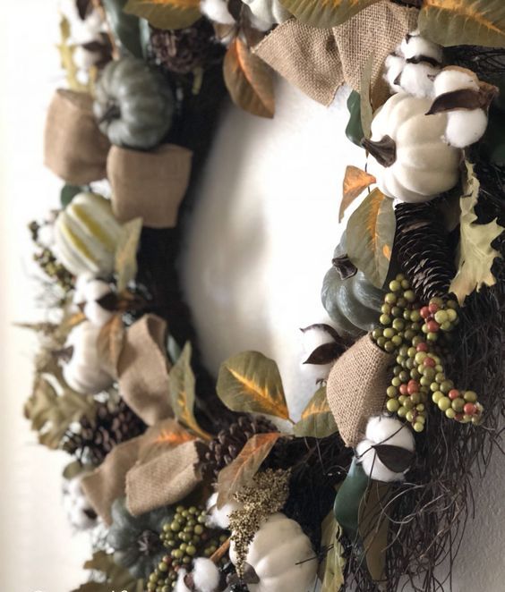 a fall wreath of faux details - pumpkins, gourds, berries, pinecones and cotton, which is dry, will last for long