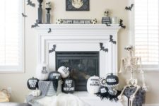 24 a stylish black and white Halloween mantel with bats, painted and stenciled pumpkins, a skull sign and skulls on stands