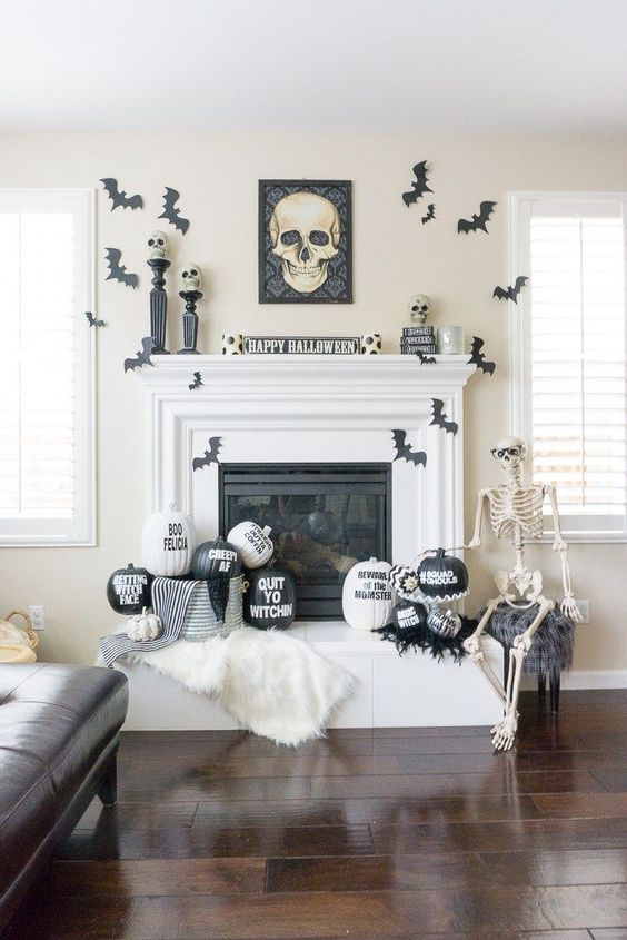 a stylish black and white Halloween mantel with bats, painted and stenciled pumpkins, a skull sign and skulls on stands