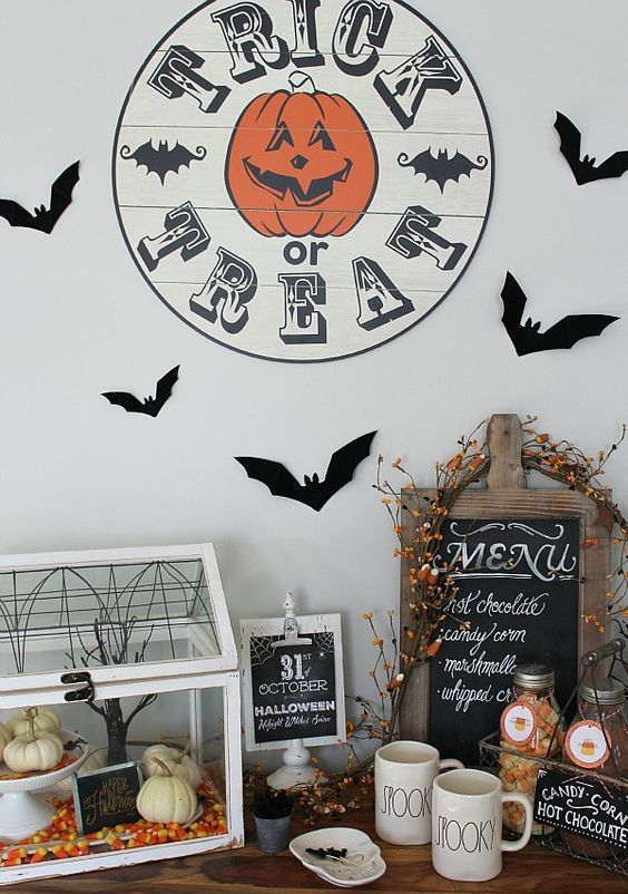 drink station decor with a treat sign, bats, a terrarium with candy corns and pumpkins and a sign plus some berries