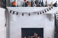 25 a bold Halloween mantel with black and orange candles, black candleholders, black and orange pumpkins, a spider bunting