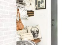 25 black bats, a skeleton, a skull pillow, a gloomy photo make this small farmhouse entryway Halloween-like