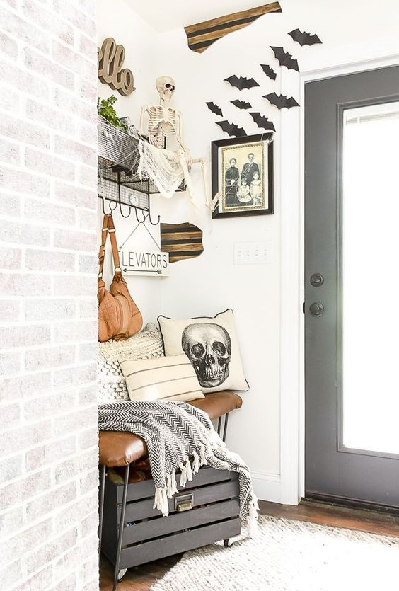 black bats, a skeleton, a skull pillow, a gloomy photo make this small farmhouse entryway Halloween-like
