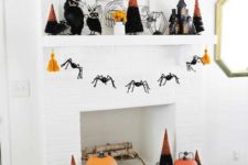 26 a bright Halloween mantel with orange pumpkins, bold black and orange trees, a cage candleholder