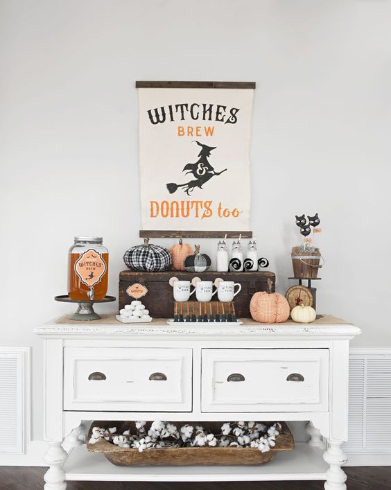 a chic farmhouse Halloween drink station with a sign, fabric pumpkins, witches' brew and some cat toppers