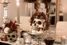 Halloween centerpieces of skulls with some leaves and berries and candles are elegant and stylish for table decor