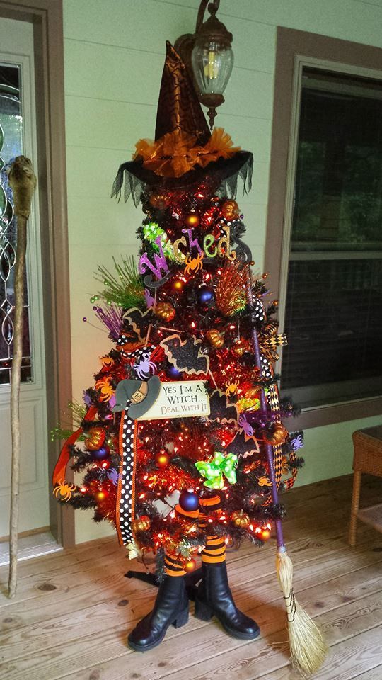 a Halloween tree imitating a witch in a hat, boots and with a broom, with lights, ornaments and hats and letters for fun