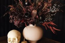 a beautiful and moody Halloween wedding centerpiece of dark and burgundy grasses, foliage and some seed pods looks jaw-dropping