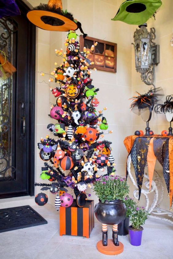 a black Halloween tree decorated in a colorful way, with orange, black and green ornaments, candy corns and ghosts