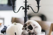 a black and white Halloween centerpiece, a black candelabra with tall and thin candles, black and white pumpkins