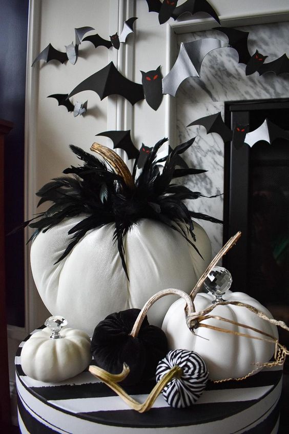 A black and white Halloween centerpiece of fabric pumpkins and feathers is a cool and long lasting idea