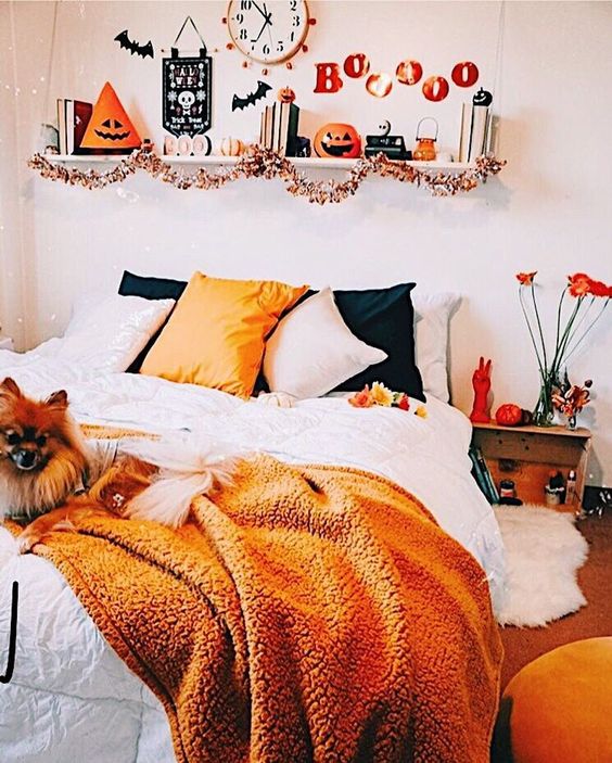 a bright Halloween bedroom with orange and black touches - bedding, letters, pumpkins and lanterns and even blooms