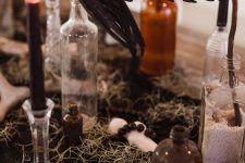 a cluster Halloween centerpiece of hay, bottles, black candles and a blackbird is a cool solution